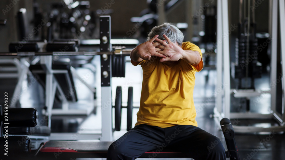 Fototapeta premium Senior strong man stretch hands in gym