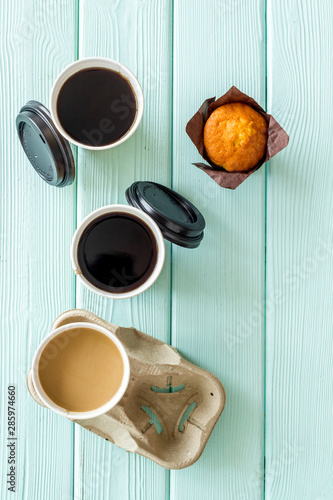 Caution: contents hot. Coffee to take away in paper cups with muffin on mint green wooden table background top view photo