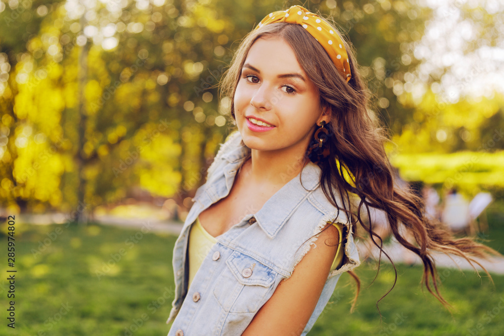 Beautiful brown-haired woman looking at the camera. A teenager walks in the park at sunset. Girl with wrap hair is smiling. Beautiful teenager. A girl with a bandana on her head, tender. Beautiful brown-haired woman looking at the camera. A teenager walks in the park at sunset. Girl with wrap hair is smiling. Beautiful teenager. A girl with a bandana on her head, tender.