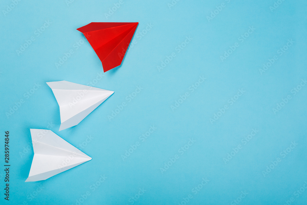 Group of white paper plane in one direction and one red paper plane pointing in different way on blue background. Business for innovative Group of white paper plane in one direction and one red paper plane pointing in different way on blue background. Business for innovative