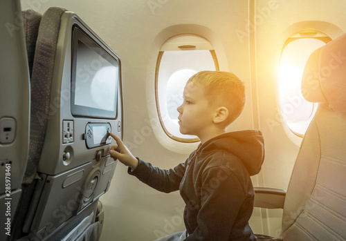 Adorable little boy traveling by airplane. Child sitting by airc photo