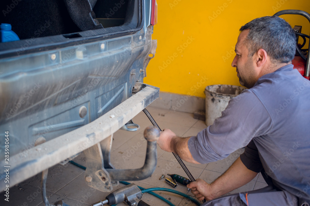 Car mechanic trying to remove back part of the car. Car repair concept