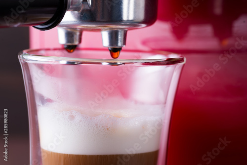 coffee machine preparing fresh latte coffee and pouring into glass at restaurant, close up