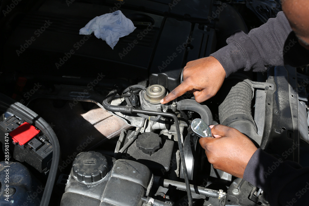 someone under the hood fixing a car someone under the hood fixing a car