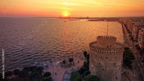 Aerial drone view of iconic historic landmark - old byzantine White Tower of Thessaloniki or Salonica at sunset with golden colours, North Greece