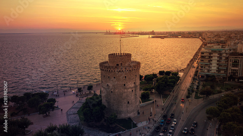 Aerial drone view of iconic historic landmark - old byzantine White Tower of Thessaloniki or Salonica at sunset with golden colours, North Greece
