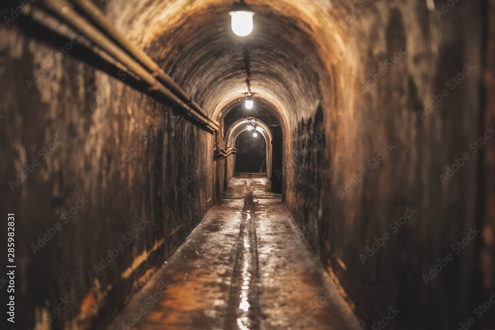 long dark narrow underground tunnel with lighting