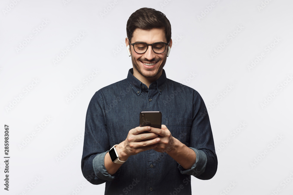 Man looking at phone, standing isolated on gray background Man looking at phone, standing isolated on gray background