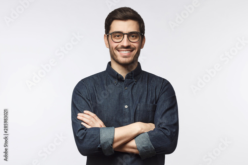 Young man wearing denim shirt standing with crossed arms isolated on gray background photo