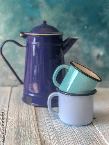 blue colored enamel teapot and mugs on a wooden table