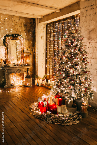 warm cozy magic evening in luxury old Christmas living room fairy tale interior design, fireplace, windows, Xmas tree decorated by lights, gifts, candles, lanterns, garland lighting.New year holiday