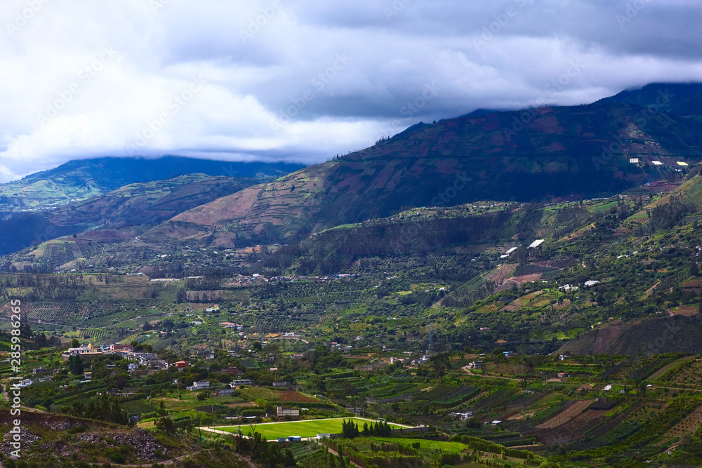 Rural hillside landscape with small farms, orchards and a pitch along the road between Ambato and Banos in Tungurahua Province in Central Ecuador. 