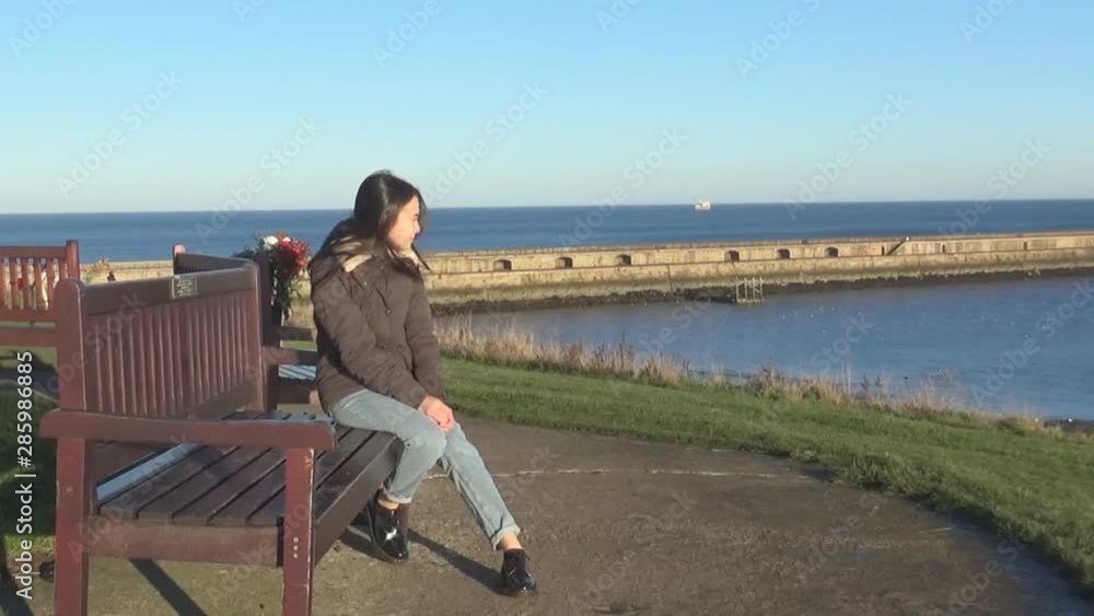 girl sitting on a bench and looking at the sea girl sitting on a bench and looking at the sea