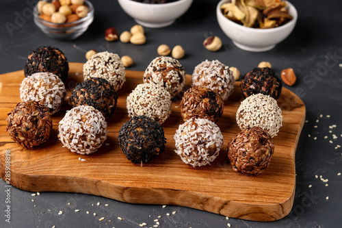 Energy balls of nuts, oatmeals and dried fruit on wooden board on dark background, horizontal orientation