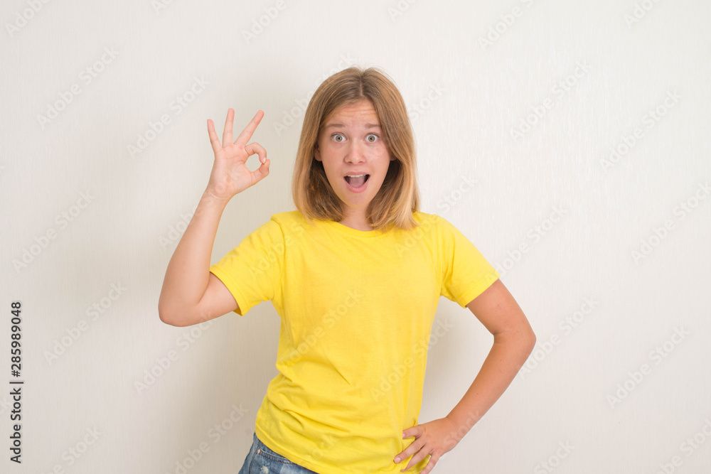 Portrait of a cheerful teenager girl showing okay gesture. Health, education and people concept. Portrait of a cheerful teenager girl showing okay gesture. Health, education and people concept.