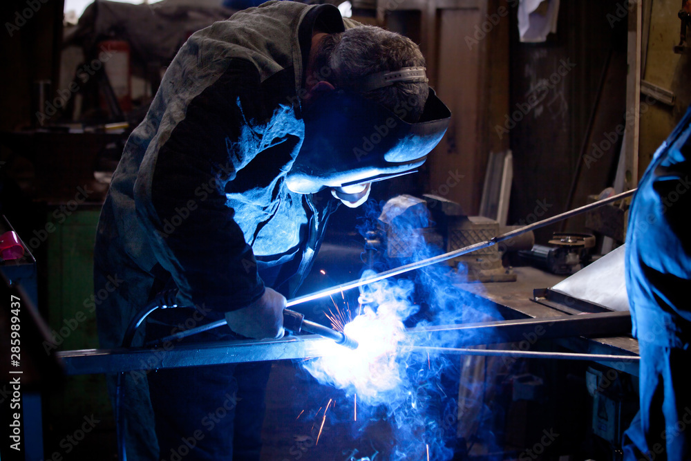 welder in mask, in the process of welding metal with bright light, smoke and sparks welder in mask, in the process of welding metal with bright light, smoke and sparks