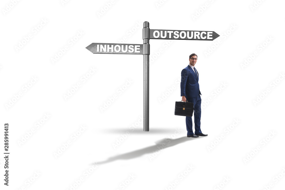 Businessman at crossroads deciding between outsourcing and inhou Businessman at crossroads deciding between outsourcing and inhou