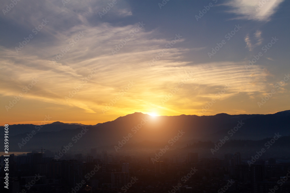 Misty city on the background of dawn in the mountains in the early morning