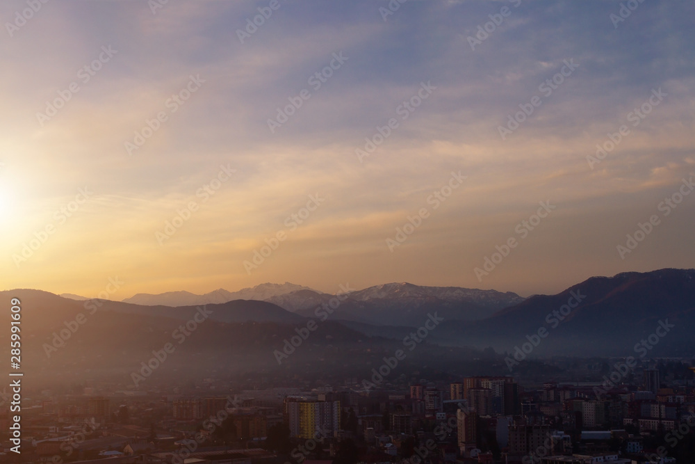 Misty city on the background of dawn in the mountains in the early morning