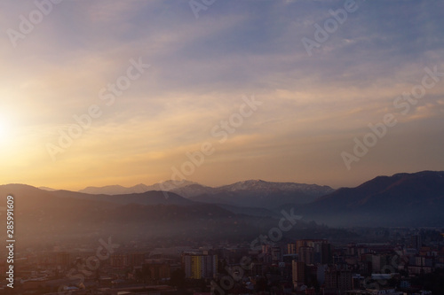 Misty city on the background of dawn in the mountains in the early morning