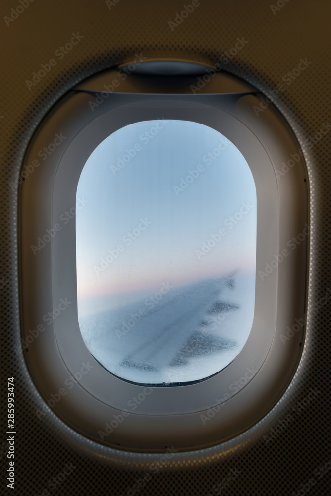 Airplane window overlooking the right wing seen from inside the airplane in flight. Focus on the window. Airplane window overlooking the right wing seen from inside the airplane in flight. Focus on the window.
