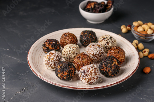 Energy balls of nuts, oatmeals and dried fruit in plate on dark background, horizontal orientation