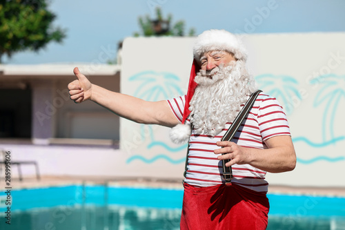 Santa Claus showing thumb-up near swimming pool at resort