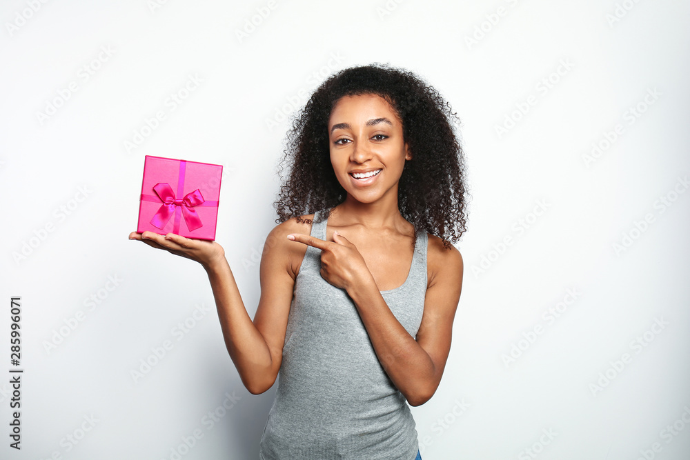 Portrait of beautiful African-American woman with gift box on white background Portrait of beautiful African-American woman with gift box on white background