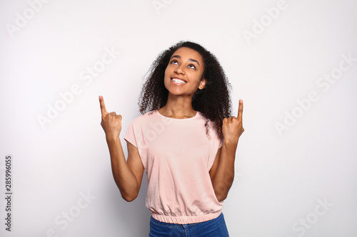 Portrait of African-American woman pointing at something on white background
