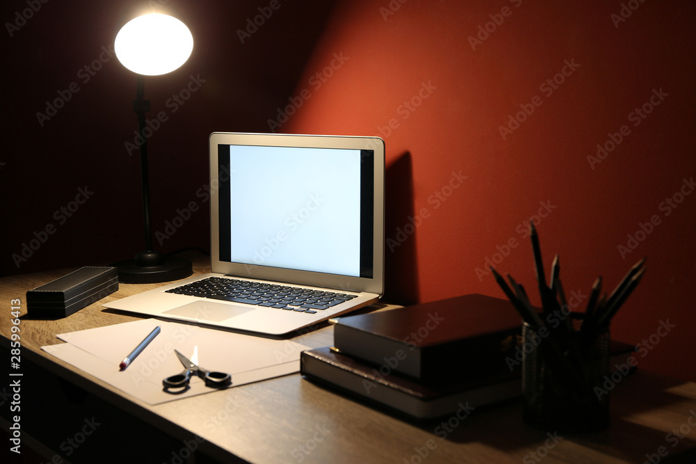 View of comfortable workplace with laptop in evening View of comfortable workplace with laptop in evening