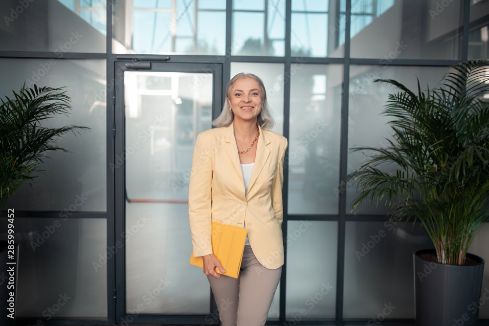 Contented senior businesswoman with a yellow paper folder Contented senior businesswoman with a yellow paper folder