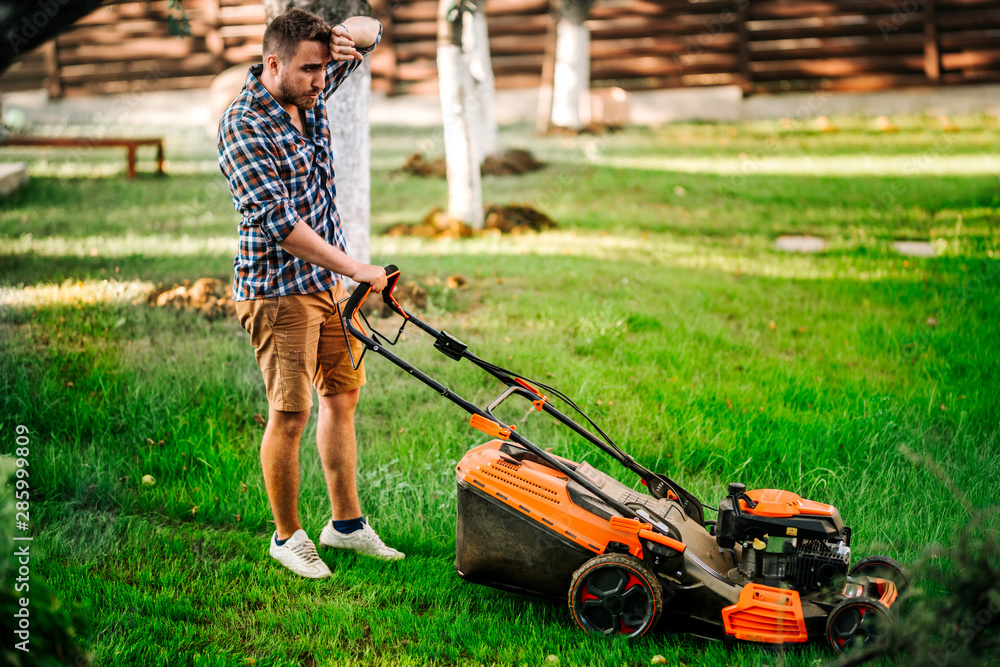 Portrait of hard working gardener using lawnmower and cutting grass Portrait of hard working gardener using lawnmower and cutting grass