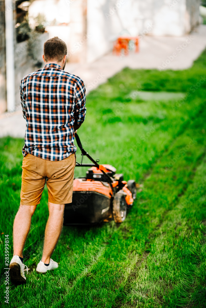 Fototapeta premium Garden maintenance details - portrait of gardener with grass mower.