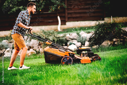 Portrait of gardener mowing the lawn using a professional lawnmower