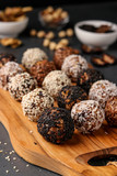 Energy balls of nuts, oatmeals and dried fruit on wooden board on dark background, vertical orientation