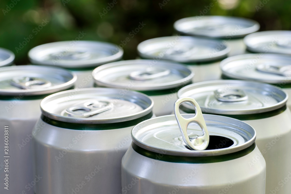Open close-up of an aluminum can of beer on the background of a group of closed beer cans Open close-up of an aluminum can of beer on the background of a group of closed beer cans