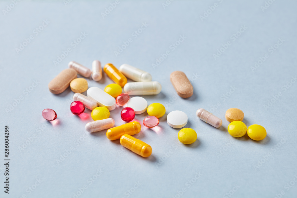 Multicolor vitamins and supplements on bright paper background. Concept for a healthy dietary supplementation. Copy space. Multicolor vitamins and supplements on bright paper background. Concept for a healthy dietary supplementation. Copy space.