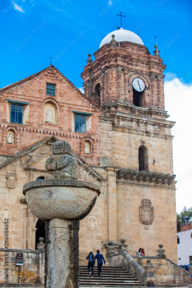 MONGUI, COLOMBIA - AUGUST, 2019: Fountain at the central square in the small town of Mongui with the historical Basilica of Our Lady of Mongui on background