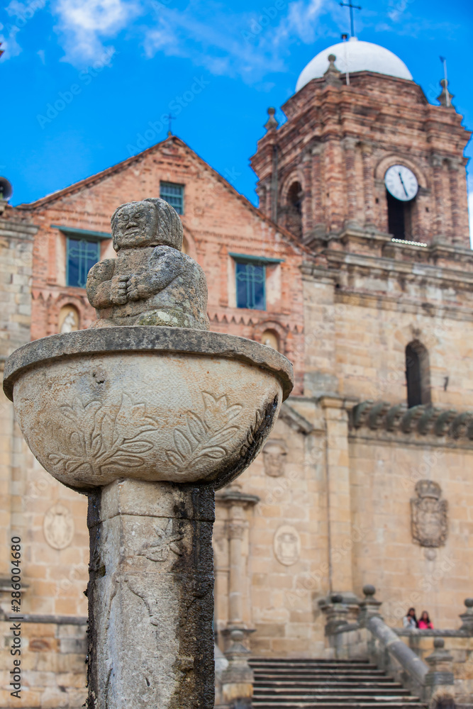 Obraz premium MONGUI, COLOMBIA - AUGUST, 2019: Fountain at the central square in the small town of Mongui with the historical Basilica of Our Lady of Mongui on background