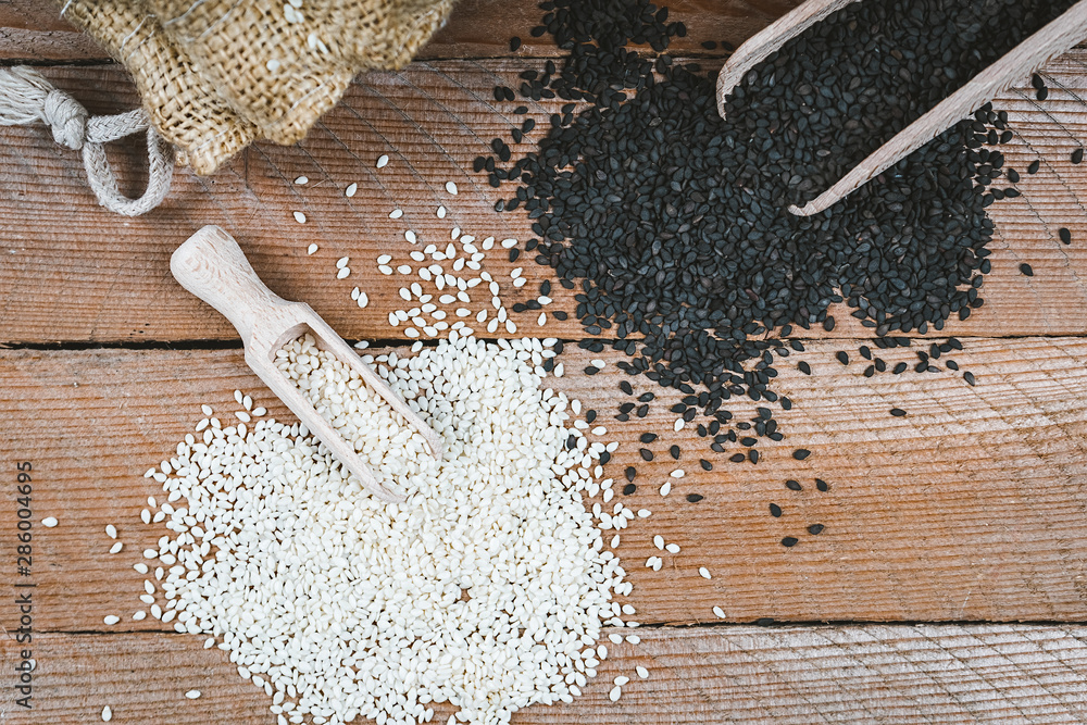 Different types of sesame seeds. White and black sesame seeds. Seasonings on a wooden background - obrazy, fototapety, plakaty 