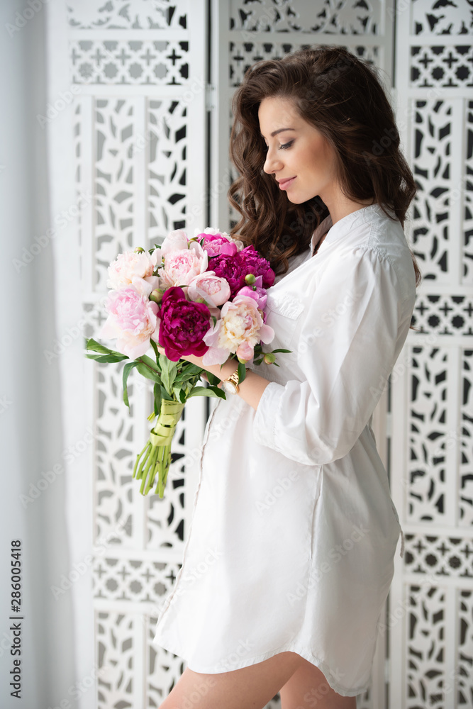 Healthy pregnancy and happy motherhood. Beautiful young pregnant woman with a bouquet of flowers on the background of an openwork wooden carved screen. Healthy pregnancy and happy motherhood. Beautiful young pregnant woman with a bouquet of flowers on the background of an openwork wooden carved screen.