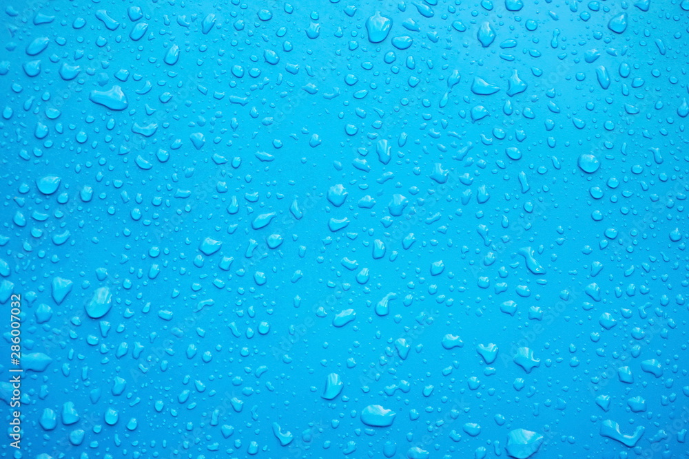 Close up of raindrops, water drops on a polished blue metal surface for background purpose. Selective focus