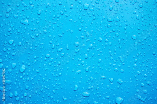 Close up of raindrops, water drops on a polished blue metal surface for background purpose. Selective focus