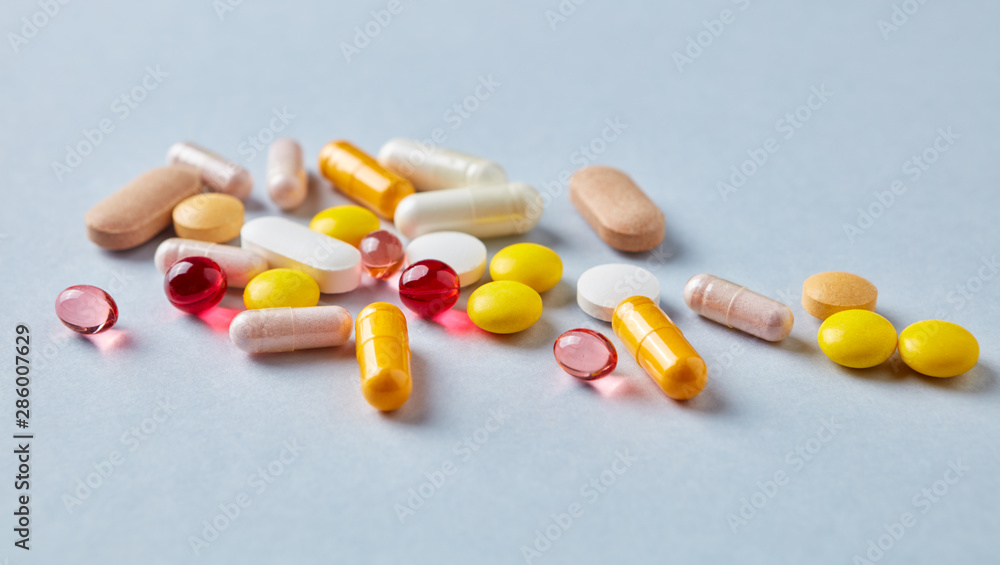 Multicolor vitamins and supplements on bright paper background. Concept for a healthy dietary supplementation. Copy space. Multicolor vitamins and supplements on bright paper background. Concept for a healthy dietary supplementation. Copy space.