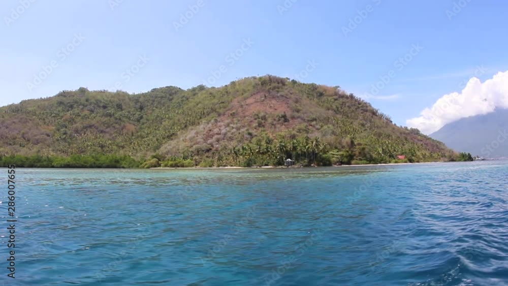 POV off the side of a boat as it passes an island in Indonesia POV off the side of a boat as it passes an island in Indonesia