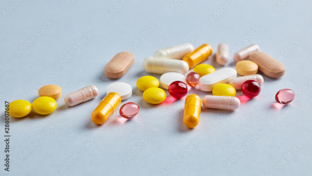 Multicolor vitamins and supplements on bright paper background. Concept for a healthy dietary supplementation. Copy space. Multicolor vitamins and supplements on bright paper background. Concept for a healthy dietary supplementation. Copy space.
