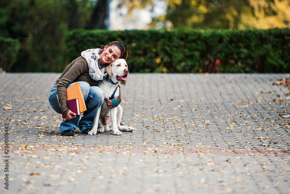 Fototapeta premium Young woman with a dog in the park. Pets and animals concept