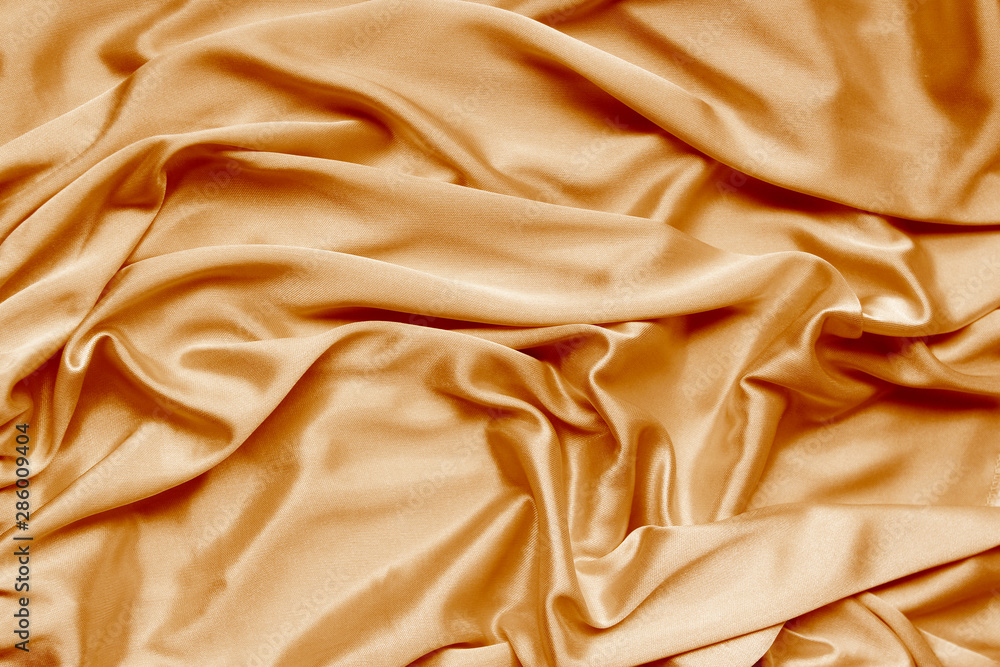 Obraz premium gold beautiful satin fabric draped with soft folds, silk cloth background, close-up, copy space