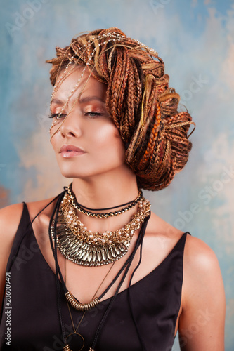 Southern flavor. Portrait of a luxurious tanned woman, pensive, stylish, with an exotic hairstyle and large jewels.