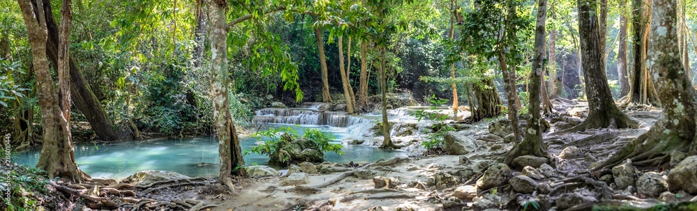 Panorama of bare tree roots and a series of beautiful short waterfalls in the dense forest of Erawan National park in Thailand - obrazy, fototapety, plakaty 